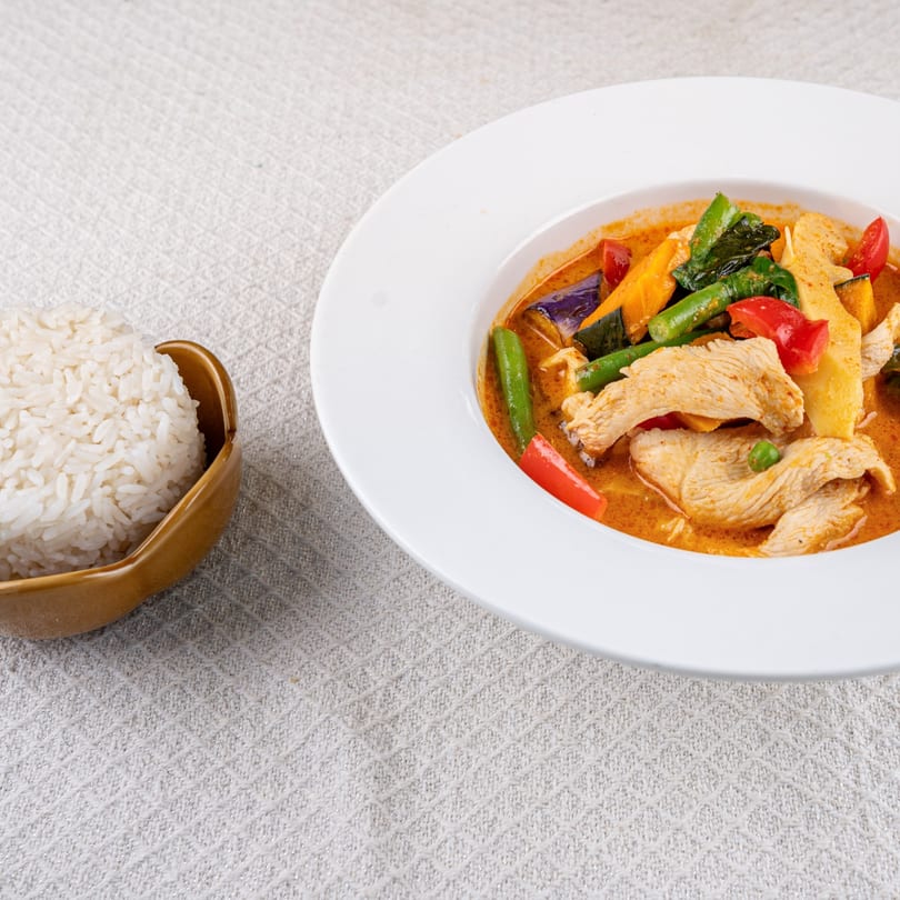 Spice Thai Kitchen's red curry with chicken and vegetables, served with a side of white rice.