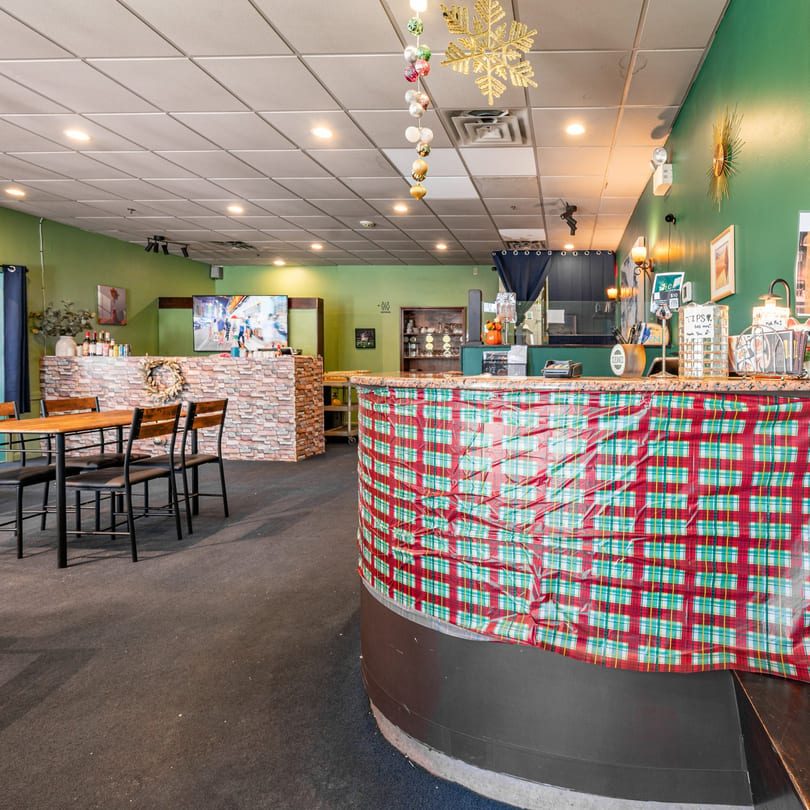 Interior of Spice Thai Kitchen with green walls, dining tables, and a bar decorated with plaid fabric.