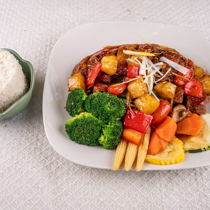 Sweet and sour chicken with pineapple, bell peppers, broccoli, and baby corn, served with rice.